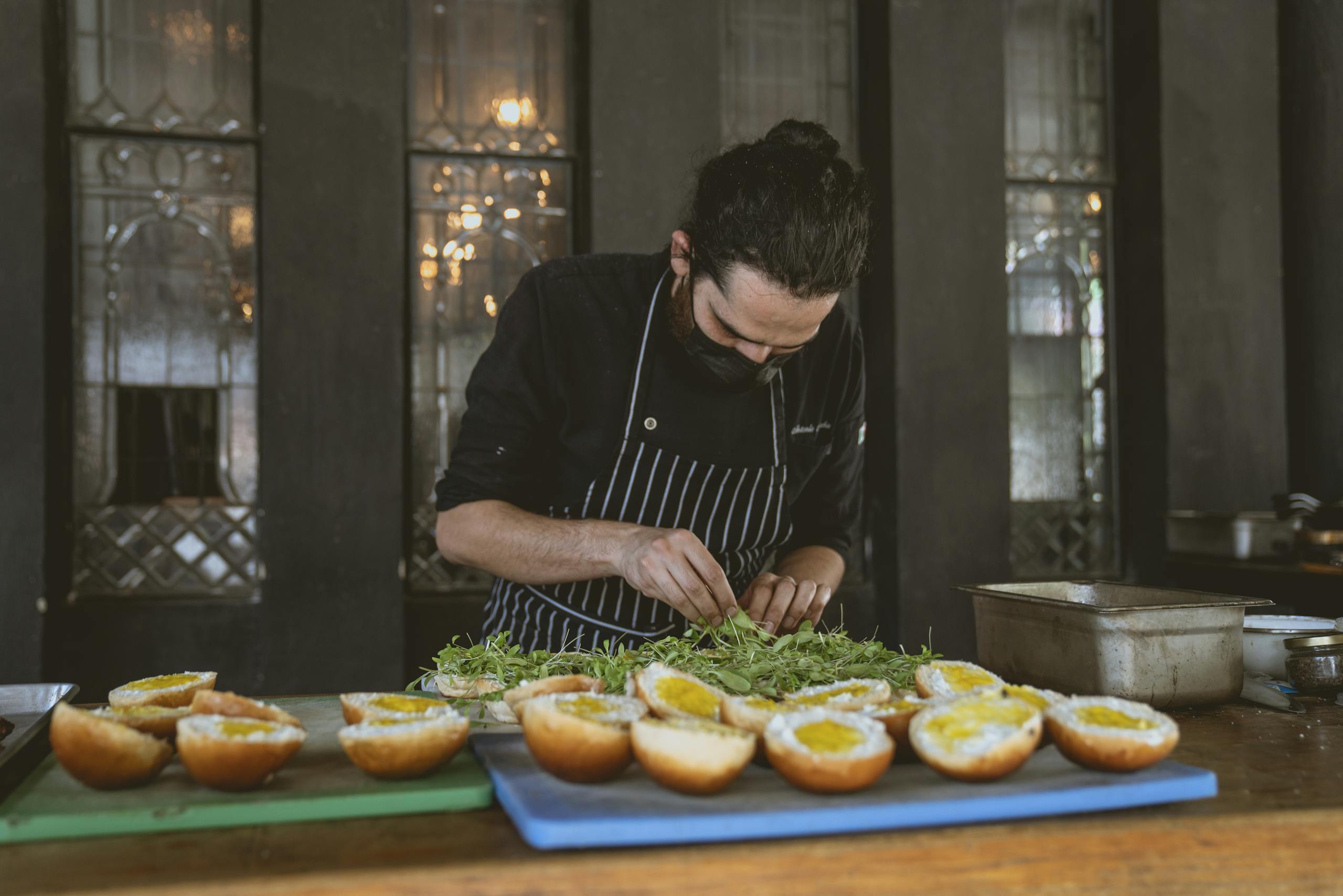 Chef focuses on preparing gourmet sandwiches with fresh ingredients in a stylish restaurant setting.