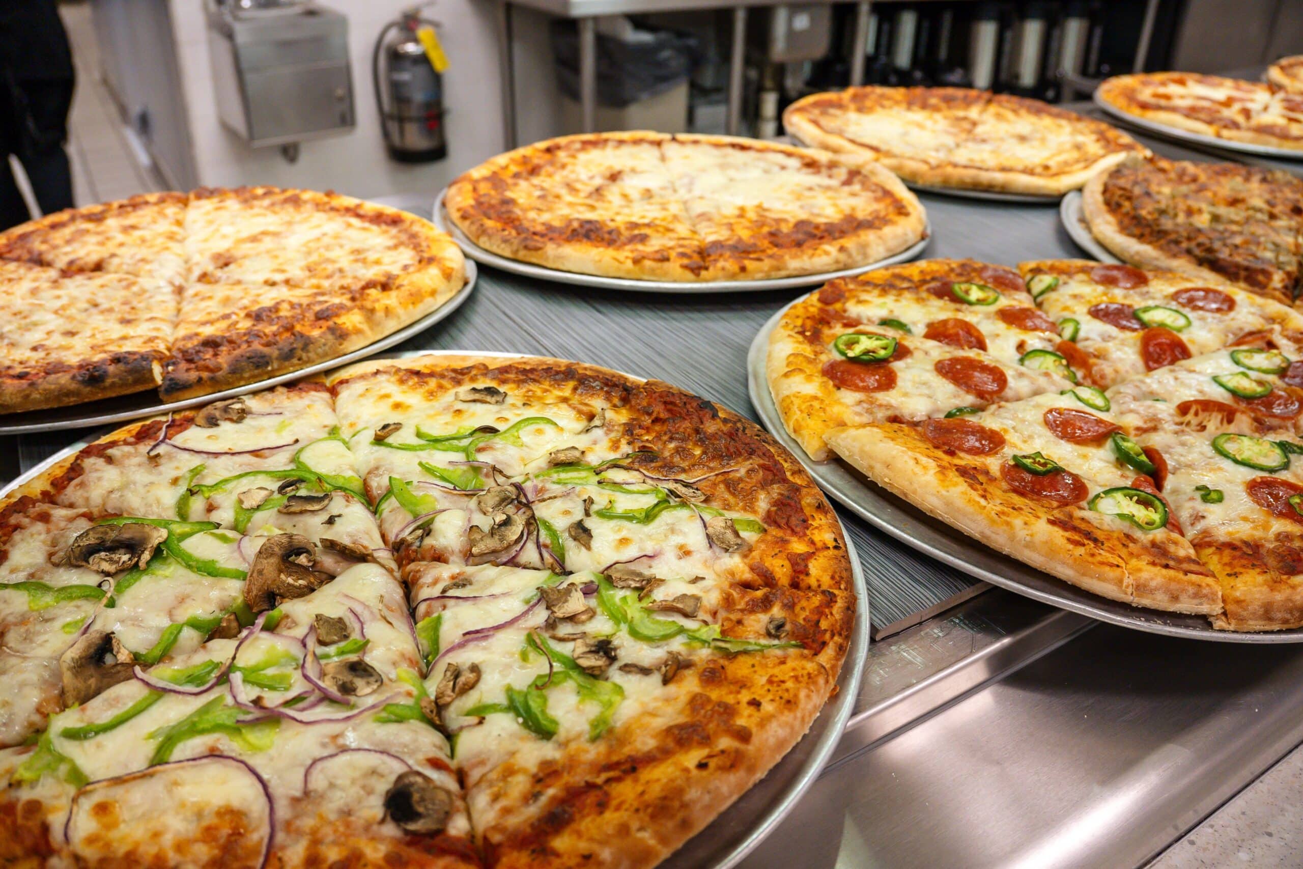 Several freshly baked pizzas on a buffet line