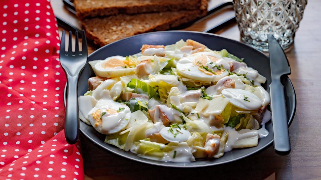 Fresh Caesar salad featuring chicken, eggs, and creamy dressing.
