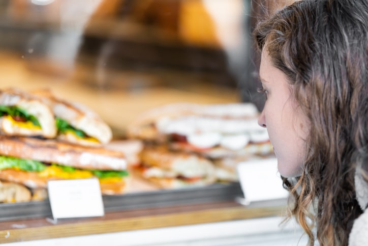Closeup of student looking at display of sandwiches behind glass in lunchroom