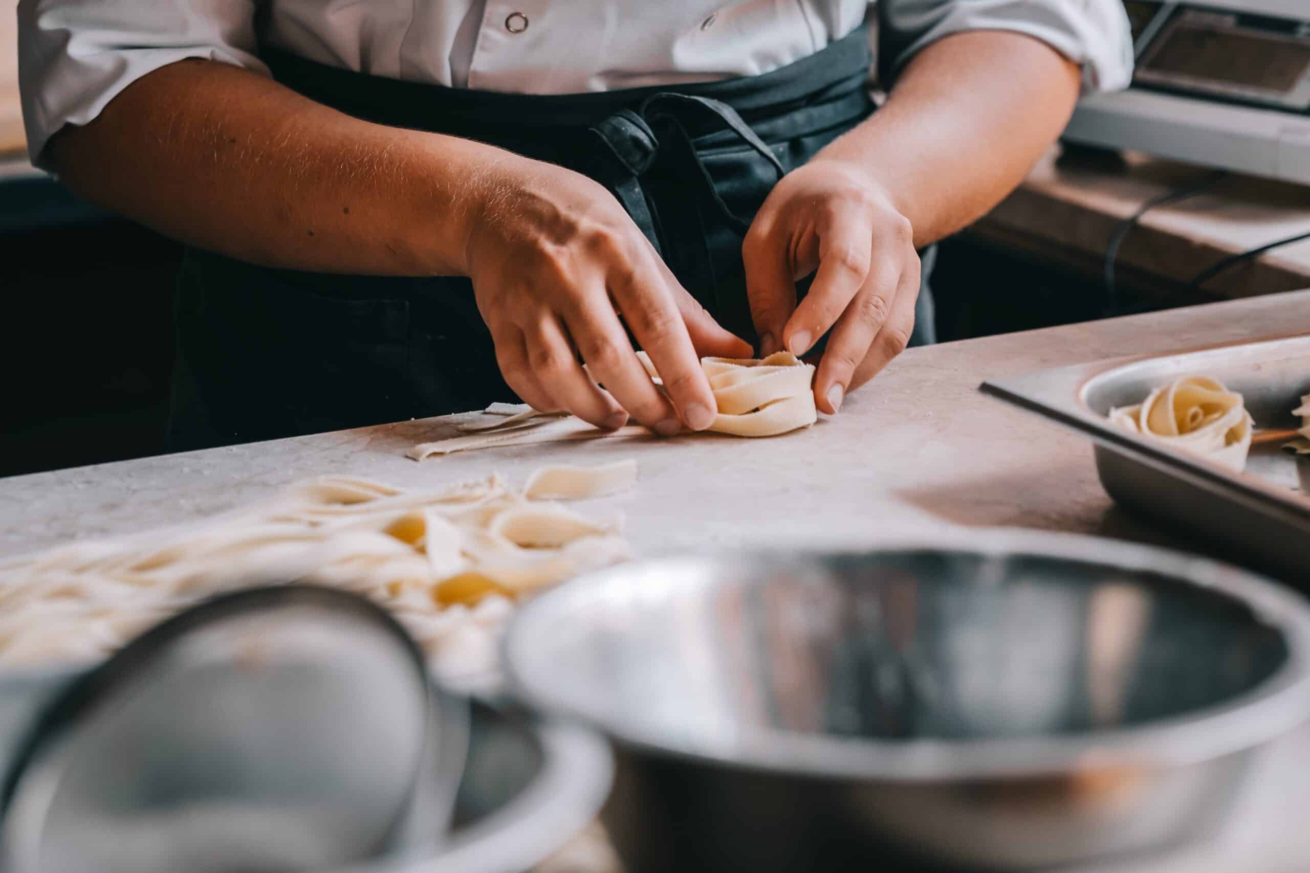 A chef hand forming homemade pasta