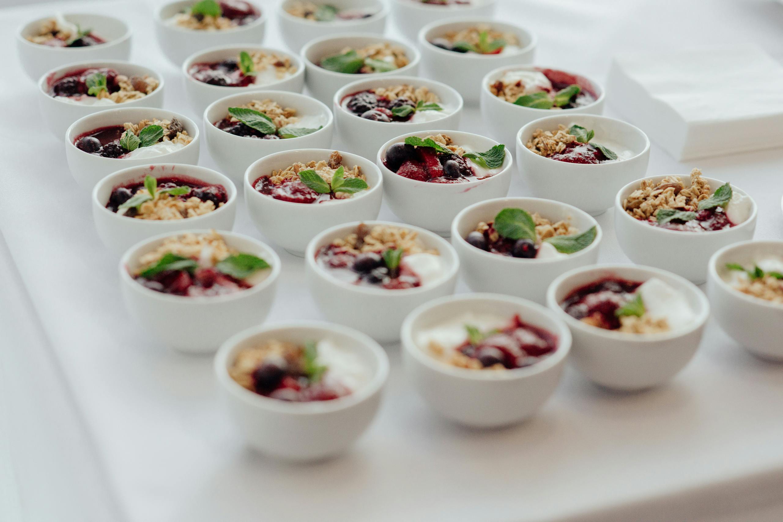 Rows of delicious yogurt parfaits topped with granola and fresh berries, perfect for a breakfast buffet.
